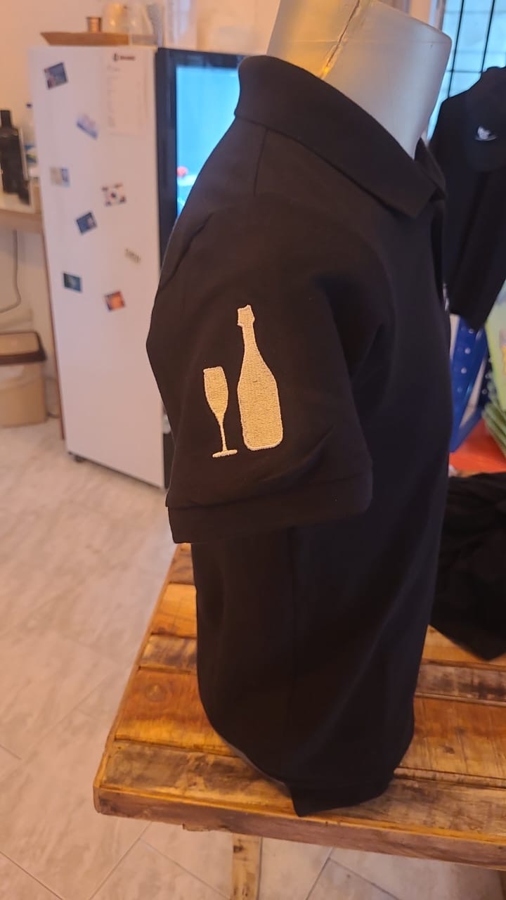 Champagne bottle and glass embroidery detail on polo sleeve
